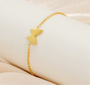 Macro shot of a gold-plated stainless steel butterfly charm bracelet on a silk background