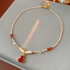 Gourd pendant necklace with freshwater pearls and beads on gray jewelry display stand