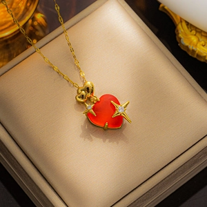Macro detail of a red heart gemstone pendant with golden star accents on a jewelry box