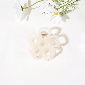 Detail of cream white flower hair claw clip with golden spring on white background