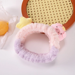Bandeau en peluche cochon rose et violet avec décor d'étoile jaune sur table