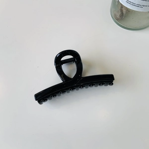 Détail d'une pince à cheveux noir mat avec un design français torsadé sur blanc