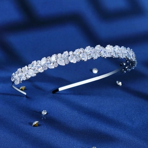Macro shot of silver zircon headband with leaf-shaped crystals on blue silk background