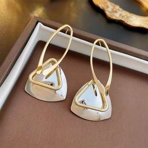 Macro shot of geometric hollow triangle earrings in gold and silver metallic finish