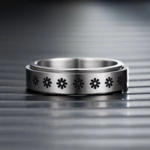 Macro view of silver rotatable daisy spinner ring with brushed titanium steel texture