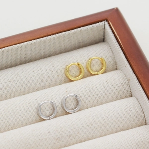 Macro view of gold and silver S925 sterling silver hoop earrings in a wooden jewelry box
