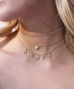 Detail of layered gold-plated necklaces with cubic zirconia pendants on a model