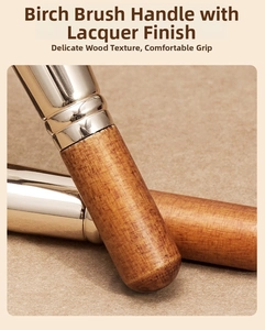 Close-up of birch wood handle with lacquer finish and glossy metal ferrule on makeup brush