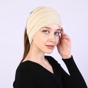 Detail of beige knitted headband showing ponytail hole and soft textured wool fabric