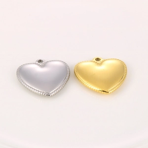 Détail de pendentifs en forme de cœur dorés et argentés avec bords perlés pour bijoux