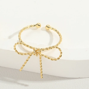 Detail of a golden bow ring with intricate twisted metal texture and open band design