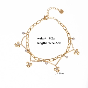 Close-up of gold bow pendants with zircon stones on double-layered link chain bracelet