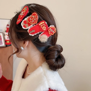 Detail view of red festive hair clips with traditional Chinese embroidery and soft pom-poms