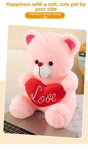 Detail of pink teddy bear plush with red heart embroidery showing Love text and soft texture