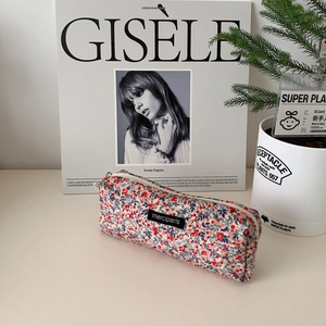 Floral corduroy makeup pouch with metal zipper and minimalist brand label on desk