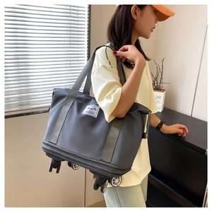 Model showing gray expandable travel bag with 360-degree wheels in home setting