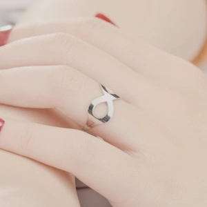 Detail of silver geometric open ring with cutout fish pattern worn on finger