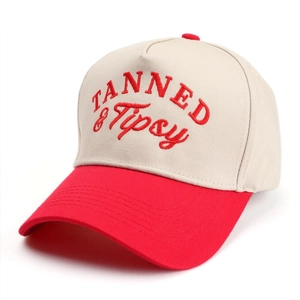 Close-up of TANNED & Tipsy embroidery on a beige and red paneled baseball cap