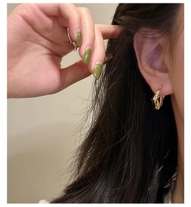 Detail of gold twisted rope hoop earrings featuring a unique braided weave texture