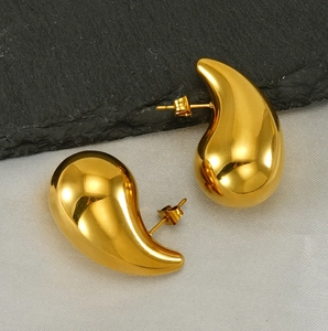 Macro shot of polished gold teardrop earrings with a smooth mirror-like metallic finish