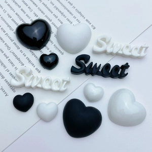 Macro shot of black and white heart-shaped resin charms with Sweet lettering for DIY crafts