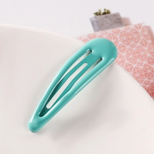 Detailed close-up of a mint green metal snap hair clip with a smooth glossy finish