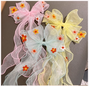 Detailed view of three pastel mesh bow hair clips with delicate floral accents and ribbons