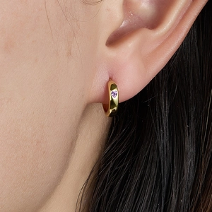 Elegant gold hoop earrings with purple heart-shaped stone on model close-up