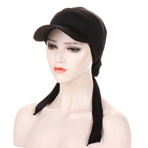 Detail of a black sunshade turban hat with long ties and pleated texture on a white model