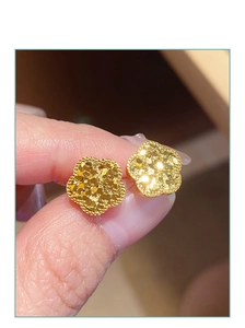 Makroaufnahme von goldfarbenen Pailletten-Blumenohrringen mit strukturierter Oberfläche