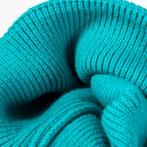 Macro close-up view of soft turquoise ribbed knit winter beanie hat textile texture