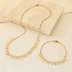 Detail of gold metal tassel necklace and bracelet set with delicate beads and charms