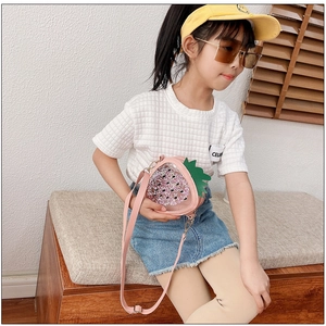 Pink strawberry jelly bag with sequins and gold chain strap worn by a young girl