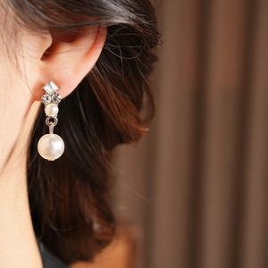 Detail of elegant silver drop earrings featuring pearls and square-cut diamond accents