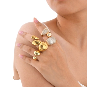 Set of chunky gold rings with zircon stones and polished pebble design on hand