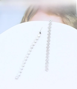 Primo piano di lunghi orecchini a nappa argentati con strass quadrati geometrici e catenine