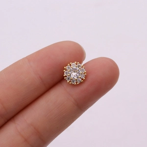Macro shot of rose gold flower stud earrings with tiny zircons held between fingers