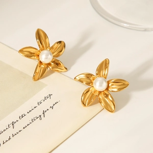 Macro shot of gold five-petal flower earrings with a white pearl center and smooth finish