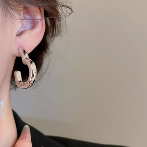 Détail de boucles d'oreilles argentées en C irrégulier avec finition miroir poli sur mannequin