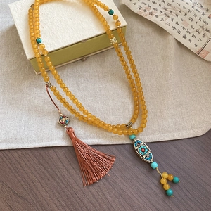 Buddhist style beaded necklace with amber beads, turquoise accents, and silk tassel