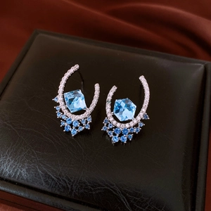 Macro view of silver earring featuring a hexagonal blue gemstone and pavé diamonds