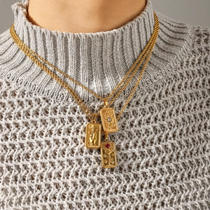 Detailed view of layered gold tarot necklaces with Sun and Star pendants on a grey sweater