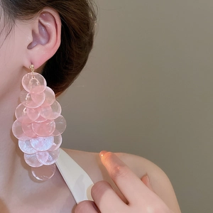 Detailed close-up of pink shell-like layered tassel earrings on a model's ear