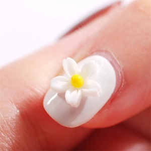 Macro detail of matte resin five-petal flower nail charms with white petals and yellow centers