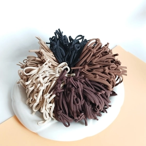 Set de gomas para el pelo elásticas en tonos tierra negro y café en plato blanco