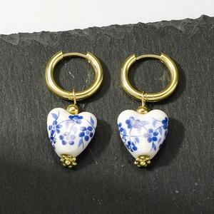 Vintage heart shaped blue floral ceramic hoop earrings with gold finish on stone background