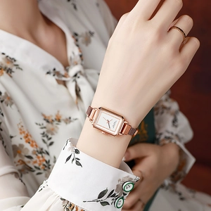 Elegant rose gold rectangular watch with Milanese mesh strap worn on a woman's wrist