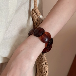 Detail of chunky acrylic chain bracelet with amber-like texture on a stylish wrist