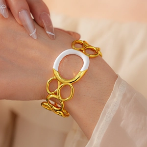 Detail of gold and white resin bangle set on wrist showing elegant metal circle links