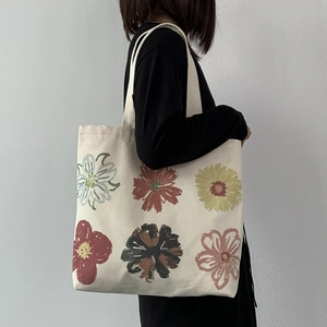 Detail of canvas tote bag featuring six colorful artistic floral prints on shoulder
